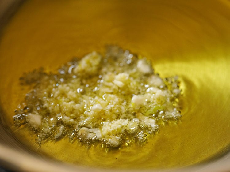 garlic added to olive oil in a steel pan