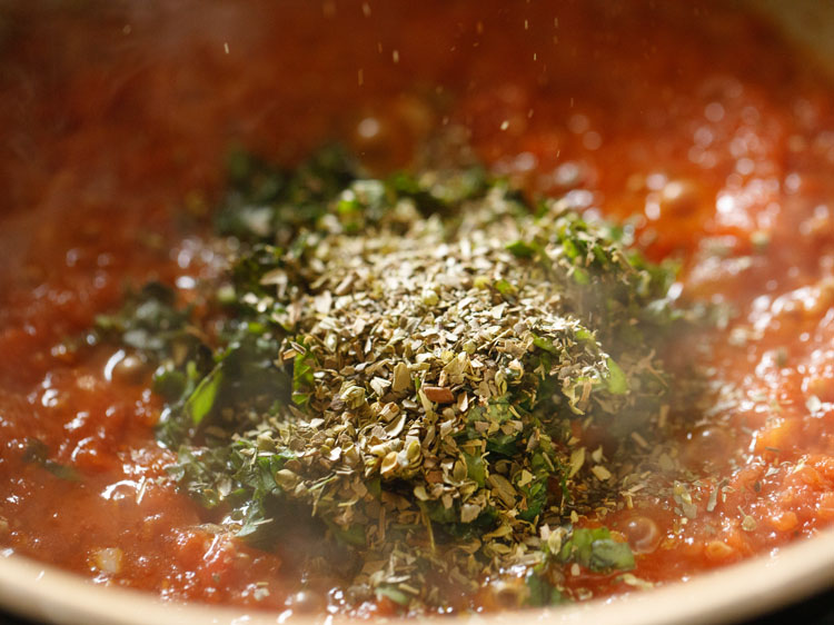 dried oregano added to pizza sauce