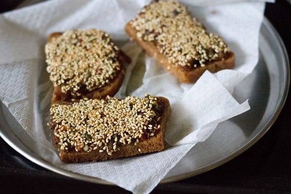 fried sesame toasts placed on kitchen paper towel. 