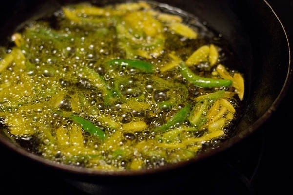 adding slit green chilies to the hot oil and frying. 