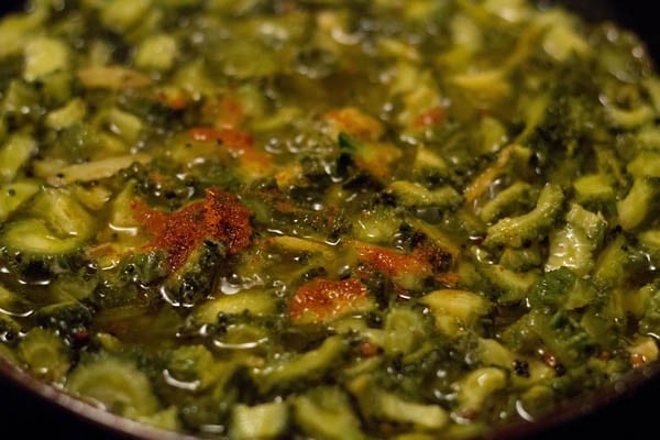 adding red chili powder to boiling pickle mixture in the pan. 