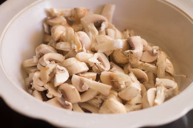 button mushrooms prepped and chopped in white bowl