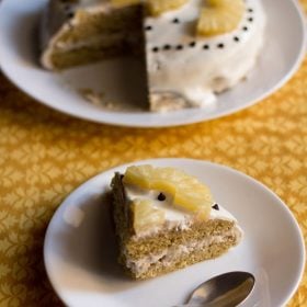 slice of pineapple pastry on white plate and pineapple cake in the background.