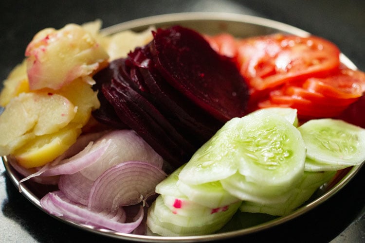 sliced beet, onion, cucumber, potato and tomato in a steel plate