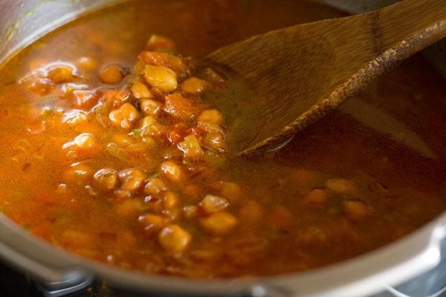 wooden spoon showing consistency of black chickpea curry consistency