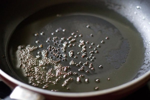 semi di senape che spruzzano nell'olio caldo