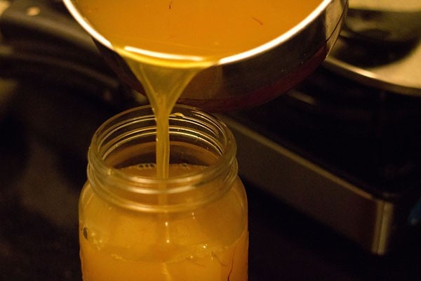 pouring prepared orange squash in sterilized glass jar. 