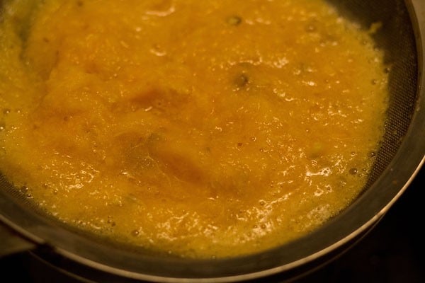 straining crushed oranges through a strainer. 