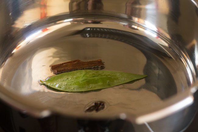 tempering cloves, tej patta and cinnamon stick in the base of a pressure cooker.