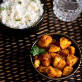 potato roast served in a bowl with a bowl of curd rice kept on the top left side and a glass of water kept on the top right side.