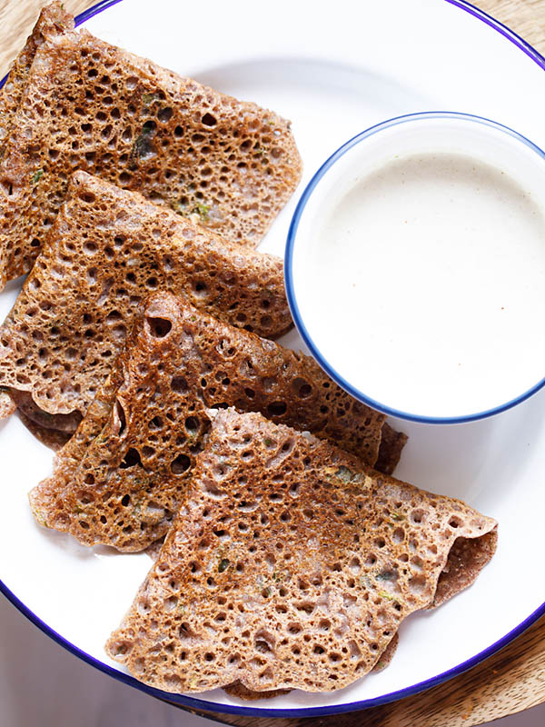 folded ragi dosa served on a white plate with coconut chutney