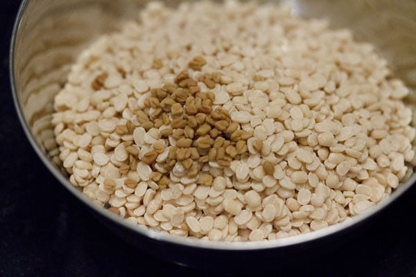 urad dal and fenugreek seeds in a steel bowl. 