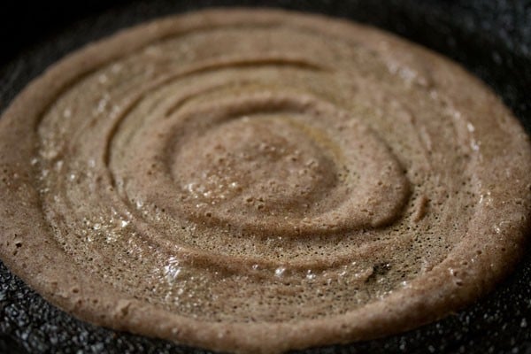 ragi dosa being cooked on skillet
