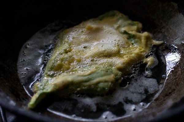 frying spinach fritters in oil in a pan