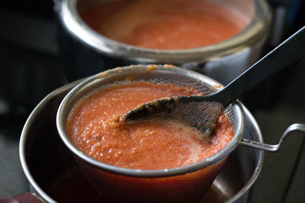 straining tomato puree mix with a spoon