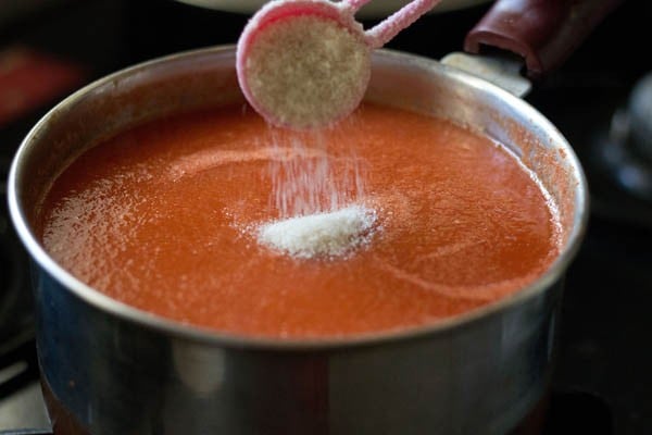 sugar being added to tomato sauce once it has thickened