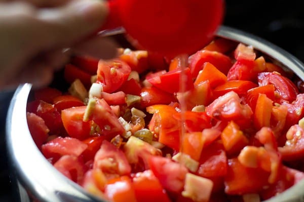 pour vinegar into chopped tomatoes, ginger, garlic, raisins and dry red chilies