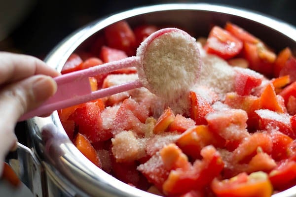 add sugar to vinegar, tomatoes, ginger, garlic, raisins and dry red chilies