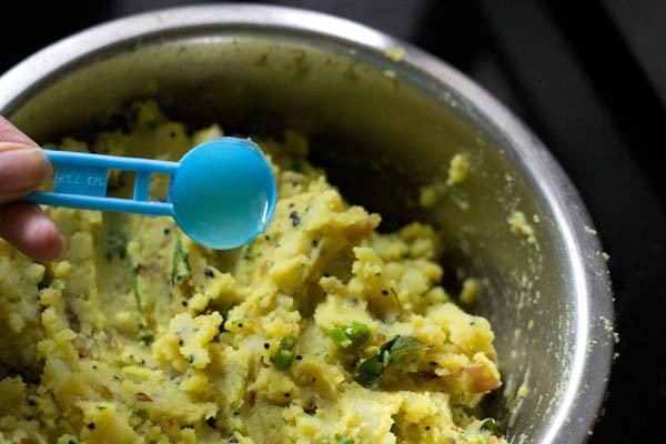 adding lemon juice to the spiced mashed potato mixture for aloo bonda recipe. 