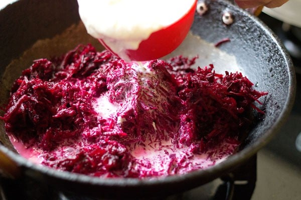 adding milk to grated beetroot in pan