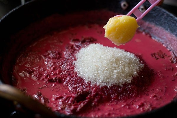 adding ghee and sugar to grated beetroot and milk mixture in pan