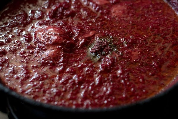 adding cardamom powder to grated beetroot and milk mixture in pan