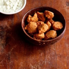 chana dal pakora served in a round bowl with a side of chutney.