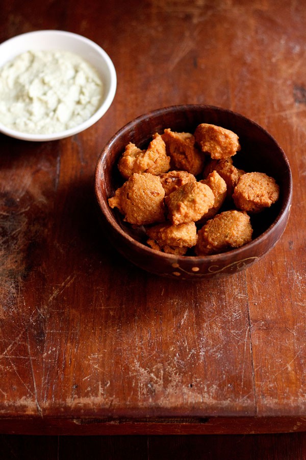 chana dal pakora served in a round bowl with a side of chutney.