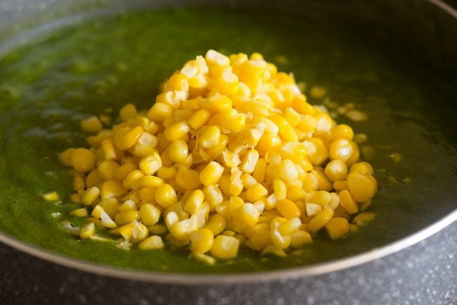 adding corn to the palak grvay