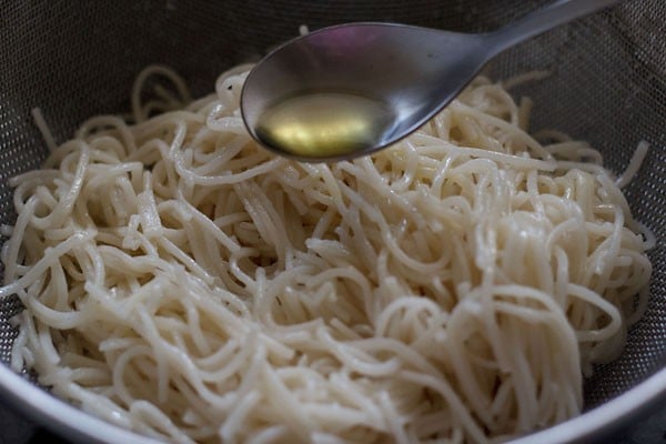 toasted sesame oil being added to cooked hakka noodles