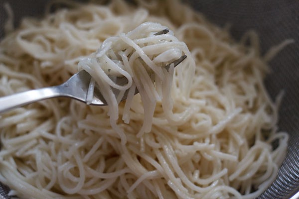 mixing hakka noodles with oil using a fork