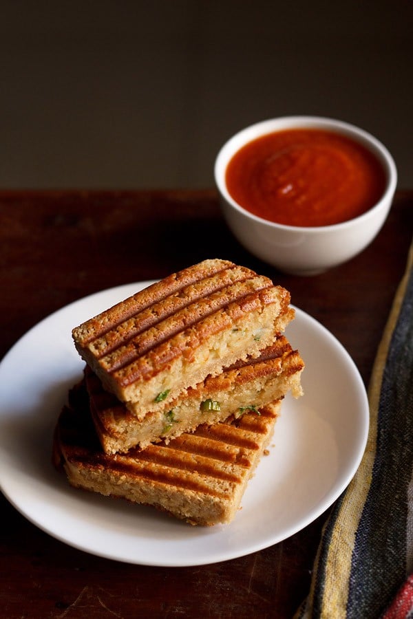 potato sandwich served on a white plate with ketchup in a bowl.