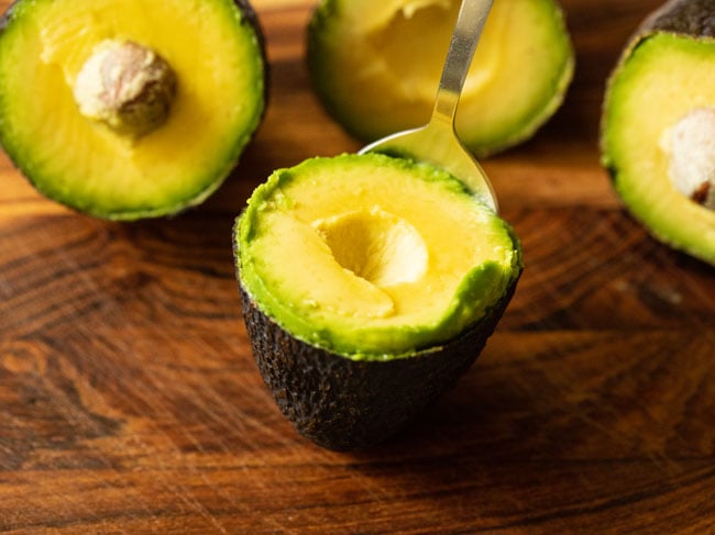 Removing the pulp with a spoon from the avocado halves.