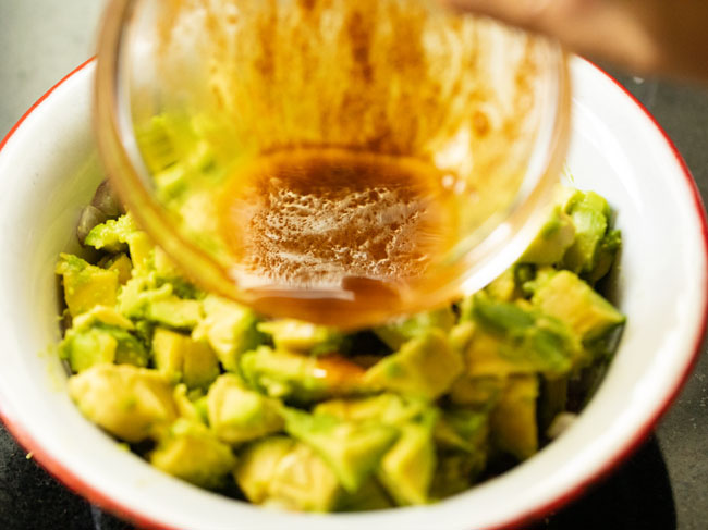 Pouring the dressing over the avocado salad.