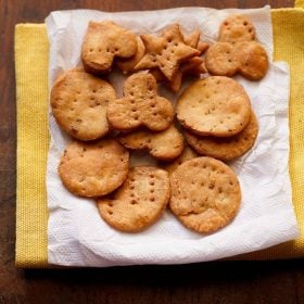 papdi placed on a kitchen paper tissue kept on a yellow colored kitchen napkin on a wooden surface with text layover.