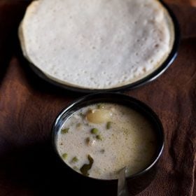 vegetable stew recipe served in a black bowl with a side of appam.