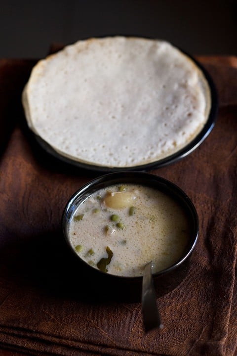 vegetable stew recipe served in a black bowl with a side of appam.