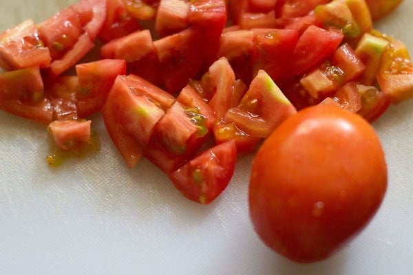 tomatoes on a white cutting board after being diced for making paneer makhani recipe