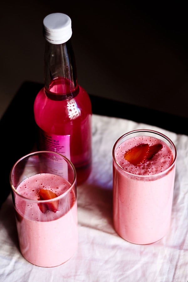 strawberry lassi garnished with strawberry slices and served in glasses.