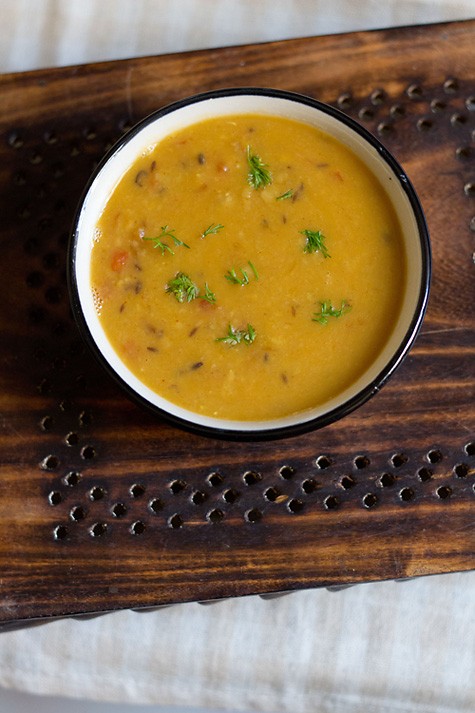 arhar dal garnished with coriander leaves and served in a black rimmed bowl. 