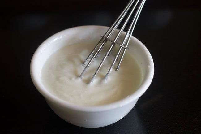 whisking curd in a bowl.