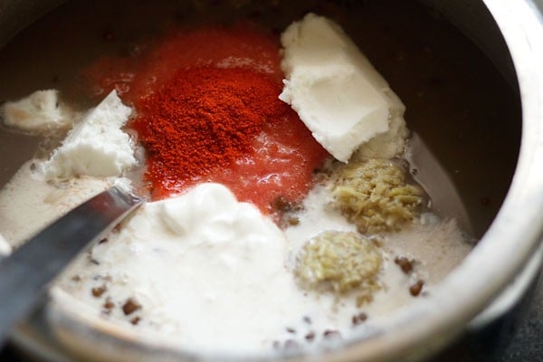 adding spices, butter, cream, water, salt to dal