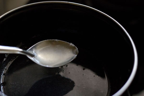 spoon showing clear agar agar solution for making vegetarian panna cotta.