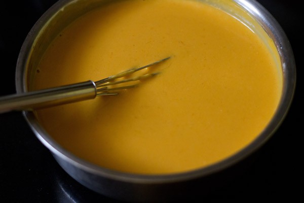 mango panna cotta mixture in a mixing bowl with a whisk – it is perfectly uniform in appearance.