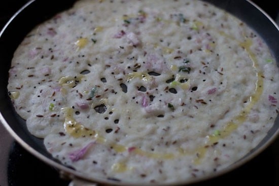 oil added on top of spread onion rava dosa. 