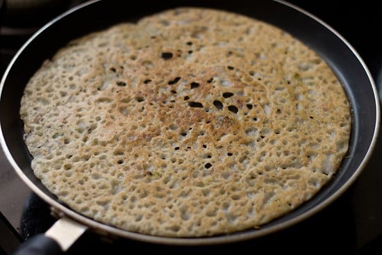 cooking onion rava dosa on pan. 