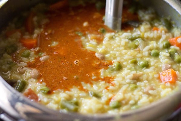 adding bisi bele bath solution to the rice, lentils and vegetables in the cooker. 