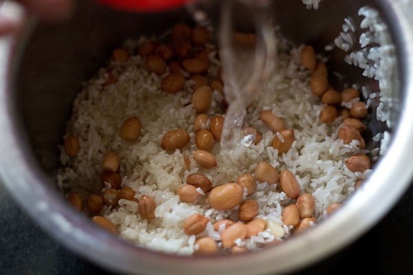 adding water to rice and peanuts for bisi bele bath recipe. 