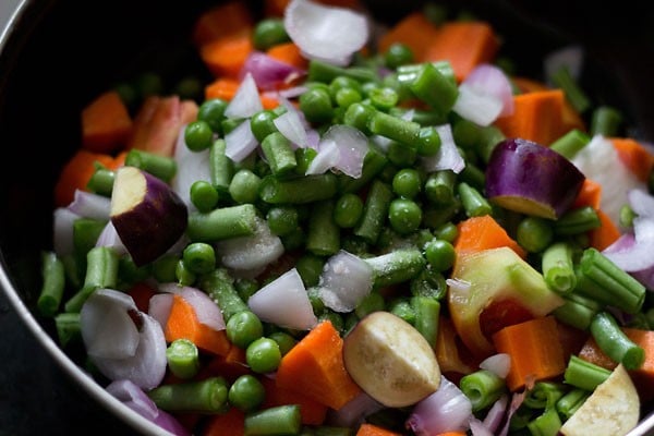 chopped vegetables and rock salt added to a pan. 