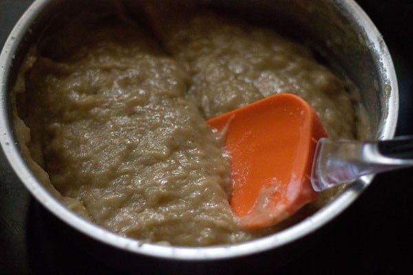 Orange spatula mixing banana cake mix in bowl